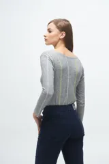 Remera gris de corte ajustado, con cuello redondo y mangas largas. Presenta líneas verticales bordadas en color verde claro y blanco.