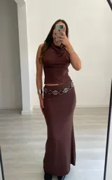 Conjunto de dos piezas color marrón oscuro, compuesto por un top halter con cuello drapeado y una falda larga ajustada.