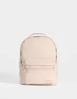 Mochila color beige de tela deportiva con textura. Tiene correa regulable, manija superior, cierre superior, doble bolsillo frontal con cierre y pullers, y bolsillos laterales.
