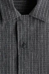 Camisa de manga corta color gris oscuro con rayas verticales, cuello resort y bolsillo de parche en el pecho. Corte recto y cierre con botones.