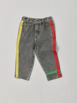 Pantalón de jean celeste con efecto lavado, corte recto y largo a la rodilla. Presenta una cinta vertical color violeta en la pierna izquierda, una cinta vertical color verde en la pierna derecha y una cinta horizontal color rosa en la parte inferior de ambas piernas.