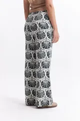 Pantalón wide leg estampado con diseño de conchas marinas color marrón sobre fondo blanco.