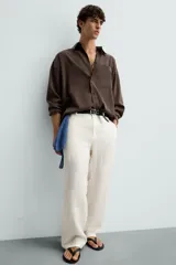 Pantalón de lino color blanco, de corte regular fit. Presenta cintura elástica, bolsillos frontales y traseros de plastrón, con cierre frontal de cremallera y botón.