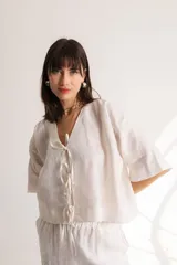 Blusa color crema confeccionada en lino, con mangas cortas, escote en V y lazos frontales.