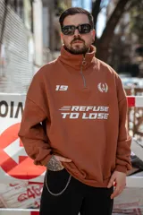 Buzo marrón con cierre medio, cuello alto y corte oversize. Estampado frontal con el número 19, un ancla con laureles y la frase "Refuse to Lose".
