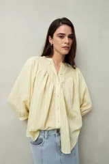 Camisa celeste a rayas verticales, de corte amplio y mangas 3/4. Presenta cuello mao, cierre frontal con botones irregulares y detalle de pespuntes y pinzas en el canesú.