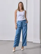 Pantalón celeste de lyocell, corte ancho, con cintura elastizada ajustable con cordón y ruedo desflecado con tajos laterales.