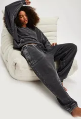 Pantalón de jogging negro con efecto gastado (acid wash) y costuras contrastantes claras. Presenta cintura con cordón ajustable y puños elásticos en los tobillos.