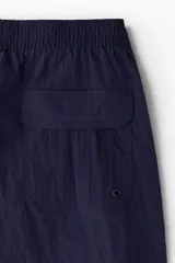 Short de baño azul marino de nylon con elástico revestido y cordón para ajustar oculto en la cintura, bolsillos laterales y bolsillo de solapa con cierre autoadherente atrás. Largo por encima de la rodilla con abertura corta en los laterales y suspensor interior en malla suave.
