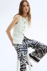 Pantalón de corte holgado con estampado de flores y hojas en azul y blanco. Modelo de tiro alto con elástico en la parte posterior de la cintura y cierre oculto con corchete en un lado. Bolsillos laterales discretos y piernas amplias con pliegues adelante y atrás.