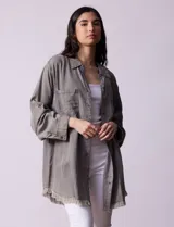 Camisa de jean celeste, marca Hester & Orchand, de corte oversize con cuello con solapa, escote en V y abertura central con botones. Delantera con bolsillos aplicados, mangas largas regulables con presilla y botón, y ruedo desflecado.