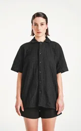 Camisa negra de manga corta con textura y cuello clásico.