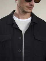 Camisa gruesa de gabardina color azul marino, con cuello clásico, cierre frontal con botones a presión, cuatro bolsillos frontales con solapa y puños abotonados.