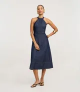 Vestido midi de jeans azul, con frente única, sin mangas y espalda descubierta.