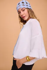 Saco tejido a máquina en lino y algodón color celeste, con silueta en línea A, mangas anchas, escote redondo con bordado en la delantera y botones de nácar. Largo por arriba de la cola.