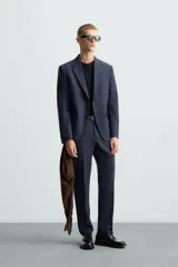 Blazer regular fit de hombre confeccionado en tejido con lana. Cuello con solapas de muesca, manga larga con puño abotonado, bolsillo de vivo en pecho, bolsillos de solapa en cadera, bolsillo interior, bajo con aberturas en espalda y cierre frontal de botonadura.