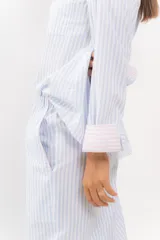 Pijama de algodón con estampado de rayas, compuesto por camisa de manga larga y pantalón recto con bolsillos y cintura elástica.