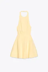 Vestido corto amarillo con cuello halter y espalda descubierta. Falda con vuelo y cierre trasero con cremallera oculta y botones ocultos en el cuello.