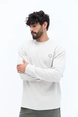 Remera de manga larga color negro, con escote redondo y un pequeño logo circular estampado en el pecho.