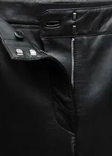 Pantalón de cuero ovino negro, de tiro alto y corte flare. Presenta trabillas, bolsillos laterales y traseros.