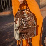 Mochila de cuero vacuno en color arena y cobre, con dos bolsillos frontales y un compartimento principal con cierre, forrada en tela de alta calidad.