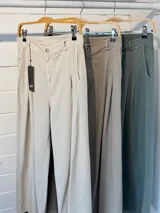 Pantalón de jean celeste de corte ancho con pinzas en la cintura y cinturón plateado con apliques florales.