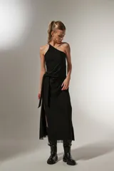 Vestido midi negro de bretel fino, con corte al cuerpo, cuello asimétrico y detalle de nudo en la cintura.