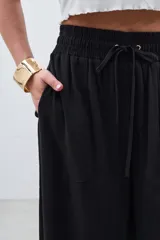 Pantalón palazzo negro de tencel con cintura elastizada y cordón ajustable.