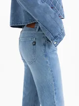 Jeans de mezclilla azul claro, tiro bajo, con corte ajustado en la parte superior y pierna recta que se ensancha ligeramente hacia el tobillo (skinny boot).