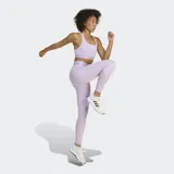 Top deportivo de compresión color lila claro, con escote redondo y espalda tipo racer-back. Presenta una banda elástica ancha bajo el busto con la inscripción 'TECHFIT' y logo de Adidas en el centro del pecho.