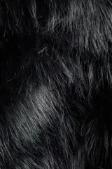 Campera corta de pelo sintético negro, con capucha oversized y cierre frontal oculto con botones a presión. Posee hombros caídos y bolsillos discretos en las costuras laterales. Es forrada.