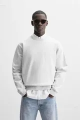 Sudadera negra de corte holgado, cuello redondo y mangas largas con puños acanalados.