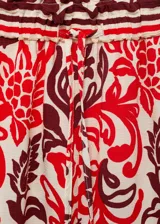 Pantalón de viscosa con estampado floral en tonos rojo, blanco y marrón. Tiene cintura elástica con cordón ajustable, corte recto y dos bolsillos laterales.