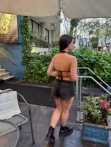 Top corto negro con escote drapeado y espalda descubierta.