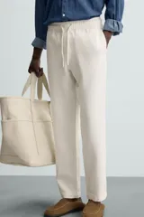 Pantalón verde oscuro de algodón con textura, corte recto, cintura elástica ajustable con cordón, bolsillos laterales y traseros de vivo.