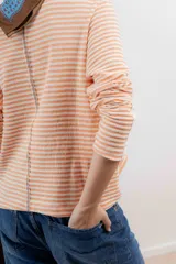 Remera de tejido de punto a rayas horizontales color naranja y blanco, de corte recto, cuello redondo y mangas largas.
