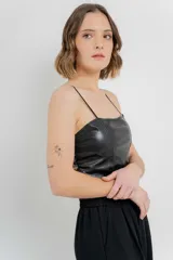 Top crop negro de cuero ecológico con espalda de encaje floral nude, tirantes finos y corte entallado.