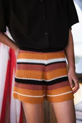 Short tejido a crochet con cintura elastizada y tiro alto, con diseño a rayas horizontales en tonos naranja, marrón, blanco y negro.