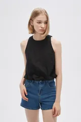 Blusa blanca de algodón sin mangas, con cuello a la base, abertura en la espalda y lazo ajustable.