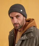 Gorro tipo fisherman corto, tejido en punto acanalado, color rosado. Presenta una pequeña etiqueta blanca cosida en el borde frontal.