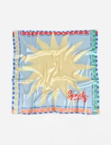 Pañuelo cuadrado de poliéster color rojo con diseño de sol celeste y blanco. Tiene borde con texto "Charrúa Uruguay Since 2015" y estrellas.