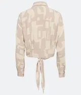 Camisa de crepé color beige con estampado geométrico en tonos neutros, cuello camisero, manga larga y cierre con botones. Tiene un lazo frontal para atar.