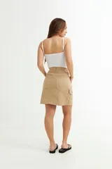 Falda corta color beige, estilo cargo, con bolsillos laterales y traseros.