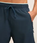 Bermuda deportiva azul marino de poliéster con elastano, con cintura elástica ajustable con cordón, bolsillos laterales con cierre y estampado localizado.