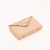 Cartera de mano tipo sobre color beige con marco metálico dorado y solapa con apliques de piedras de colores.