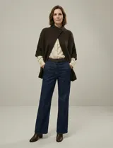 Capa o poncho tejido color verde esmeralda, con cuello polera alto que se cierra con un botón grande en el lateral. Presenta mangas cortas estilo japonesa y un calce amplio.