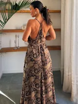 Vestido largo tipo solera, color turquesa con estampado paisley en tonos marrones y dorados. Diseño con escote halter anudado al cuello y abertura frontal central en color liso.