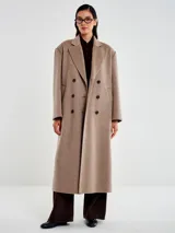 Tapado largo de corte oversize confeccionado en mezcla de lana. Presenta un diseño de doble botonadura frontal con botones oscuros, solapas de muesca y bolsillos laterales. Cuenta con interior acolchado y mangas forradas para mayor confort.