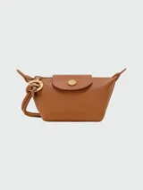 Monedero Longchamp Le Pliage Xtra de cuero color marrón caramelo, con cierre de cremallera y solapa con botón a presión. Incluye correa de mano y charm con el logo de la marca.