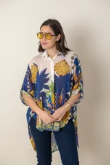 Camisa italiana de viscosa estampada con diseño abstracto en tonos azul, amarillo y verde sobre fondo natural, de corte irregular y mangas 3/4.